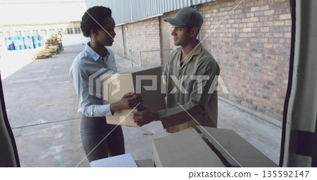 Businesswoman in blue shirt receiving cardboard box from delivery worker at dock, with pallets Businesswoman in blue shirt receiving cardboard box from delivery worker at dock, with pallets 135592147