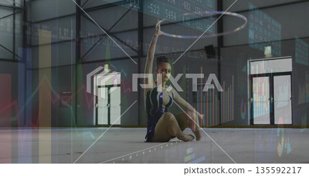 Holding metallic hoop overhead, teenage gymnast training on sports hall floor mat, with exit doors 135592217
