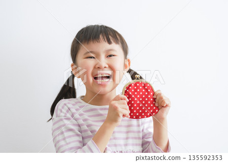 Child holding a clasp wallet (money/pocket money) Child holding a clasp wallet (money/pocket money) 135592353
