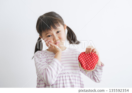 Child holding a clasp wallet (money/pocket money) 135592354
