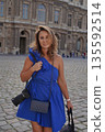 Woman in Blue Dress Posing with Camera in Courtyard 135592514