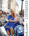 Stylish Woman in Blue Dress Sitting on Scooter 135592520