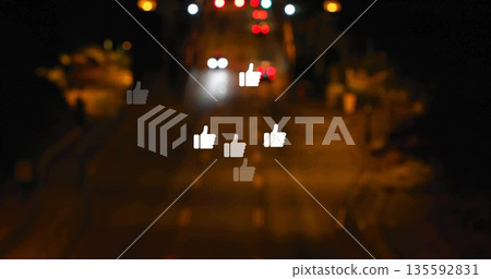 Floating six thumbs-up icons glowing above urban roadway at night, with streetlights and headlights 135592831