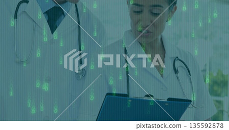 Doctors wearing white coats and stethoscopes examining tablet in clinic, with binary code overlay Doctors wearing white coats and stethoscopes examining tablet in clinic, with binary code overlay 135592878