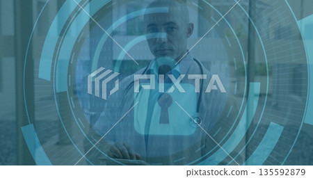 Doctor wearing lab coat reviewing on tablet in hospital corridor, with digital security overlay Doctor wearing lab coat reviewing on tablet in hospital corridor, with digital security overlay 135592879