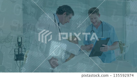 Pointing doctors in coat and scrubs reviewing clipboard with patient by IV stand in hospital room Pointing doctors in coat and scrubs reviewing clipboard with patient by IV stand in hospital room 135592974