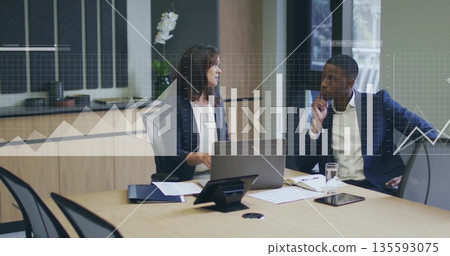 Colleagues in suits reviewing bar-line charts in office with laptop, tablet, documents, phone 135593075