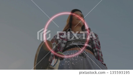Holding skateboard, skateboarder wearing plaid shirt standing in urban space, with neon ring effect 135593195