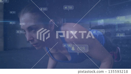 Woman wearing blue top and leggings doing push-up in fitness studio, with social media icons Woman wearing blue top and leggings doing push-up in fitness studio, with social media icons 135593218