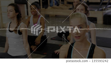 Leading yoga instructor guiding four participants in activewear posing in studio, mats, copy space 135593242