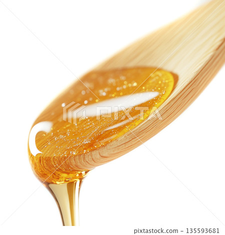 Honey drips from a wooden spoon, highlighting its golden texture and viscosity in a close-up view 135593681