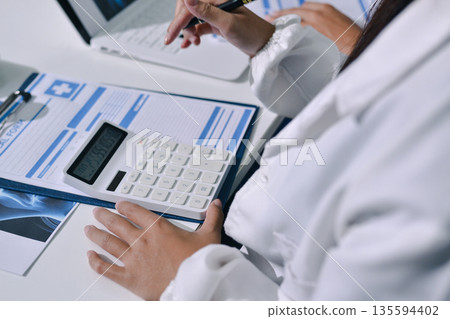 Doctor Explaining X-Ray Results to a Patient Using a Digital Device 135594402