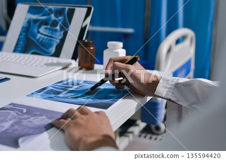 Doctor Explaining X-Ray Results to a Patient Using a Digital Device 135594420