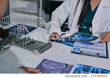 Doctor Explaining X-Ray Results to a Patient Using a Digital Device 135594424