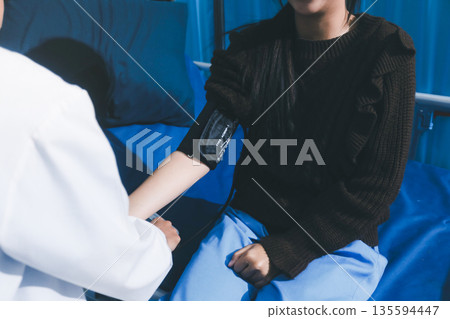 Doctor examining young girl, measuring blood pressure, using medical blood pressure monitor. Concept of school entry medical exam. Doctor examining young girl, measuring blood pressure, using medical blood pressure monitor. Concept of school entry medical exam. 135594447