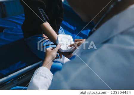 Doctor in hospital using manual blood pressure monitor to measure woman patient blood pressure and pulse. Doctor in hospital using manual blood pressure monitor to measure woman patient blood pressure and pulse. 135594454