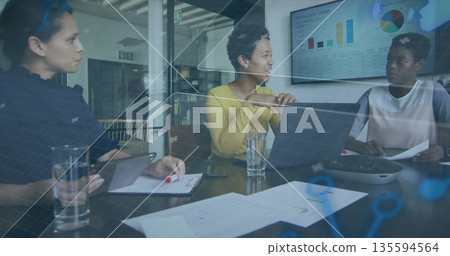 Speaking woman in yellow sweater leading meeting in modern glass conference room with laptop charts 135594564