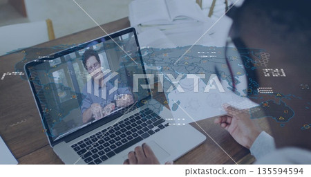 Colleague holding map and discussing global data on laptop at office desk with headset, copy space 135594594