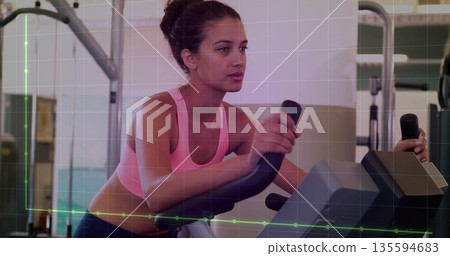 Cycling woman in pink sports bra, dark leggings on stationary bike at gym, with performance metrics Cycling woman in pink sports bra, dark leggings on stationary bike at gym, with performance metrics 135594683