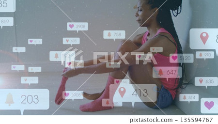 Adjusting sock woman wearing pink top on studio floor with social media icons, copy space Adjusting sock woman wearing pink top on studio floor with social media icons, copy space 135594767