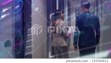 Suited professionals walking through office hallway, viewing holographic charts with printed report Suited professionals walking through office hallway, viewing holographic charts with printed report 135594812