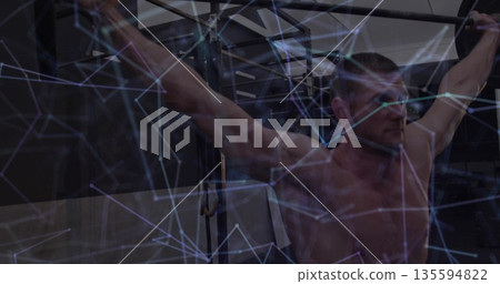 Gripping metal pull-up bar, shirtless muscular man holding pull-up rig in gym with digital graphics Gripping metal pull-up bar, shirtless muscular man holding pull-up rig in gym with digital graphics 135594822