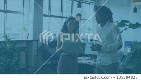 Discussing woman holding laptop with coworker at office, with smartphone coffee cup and notebooks 135594825