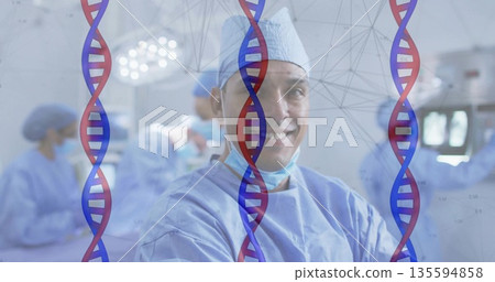 Working female surgeon wearing blue scrubs in OR, with monitors and DNA helix overlay Working female surgeon wearing blue scrubs in OR, with monitors and DNA helix overlay 135594858