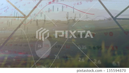 Overlaying steel transmission towers spanning field at sunrise, with financial charts and pie chart 135594870