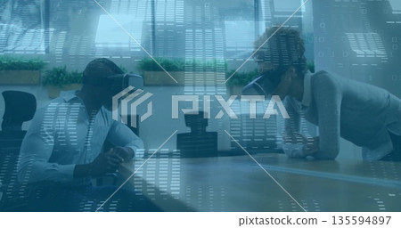 Collaborating colleagues wearing VR headsets in conference room with table and code overlay 135594897