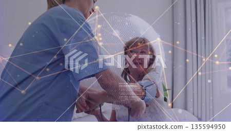 Nurse in blue scrubs fitting blood pressure cuff on arm in patient room, plant on windowsill 135594950