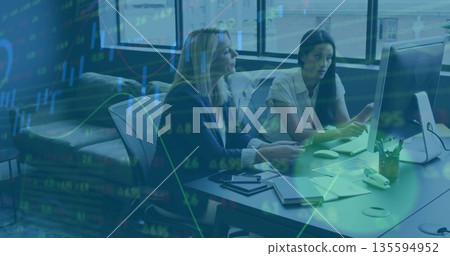 Collaborating experienced women reviewing reports at office desk, with financial data overlay 135594952