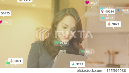 Holding tablet computer and viewing notification icons in warm home kitchen wearing charcoal blazer 135594988