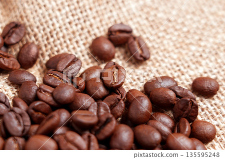 Close-up of freshly roasted coffee beans on rough burlap. Rustic View Close-up of freshly roasted coffee beans on rough burlap. Rustic View 135595248
