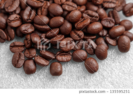 Close-up of scattered coffee beans on a gray plastic surface Close-up of scattered coffee beans on a gray plastic surface 135595251