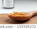 Natural turmeric capsules with curcumin powder in a wooden spoon on rustic table background. Herbal dietary supplement.  Alternative medicine concept 135595272