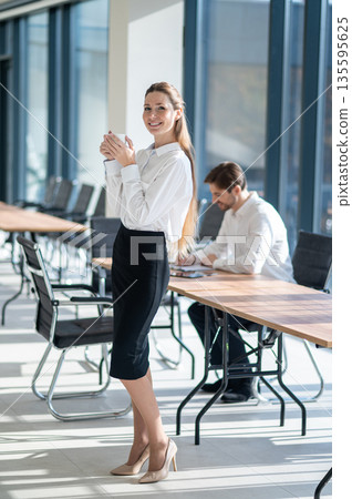 Cute young business woman enjoying her tea and looking contented 135595625