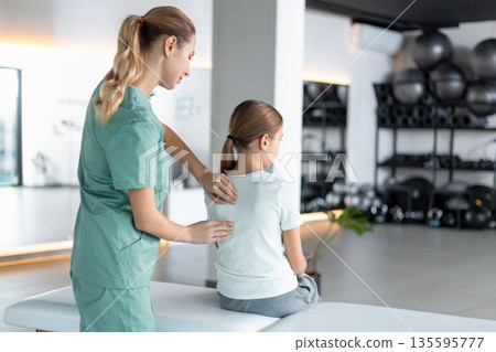 Woman therapist working with girl during rehab session 135595777