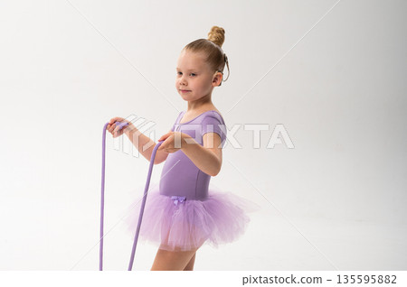 Young ballerina with cochlear implant looking at rope in her hands. Copy space. Symbol of awareness, concentration, and childhood inclusion through art and technology. 135595882
