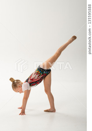 Young gymnast with a cochlear implant performs a forward split balance on the floor. Rehabilitation, auditory technology, and physical development through rhythmic gymnastics and inclusive dance Young gymnast with a cochlear implant performs a forward split balance on the floor. Rehabilitation, auditory technology, and physical development through rhythmic gymnastics and inclusive dance 135595888