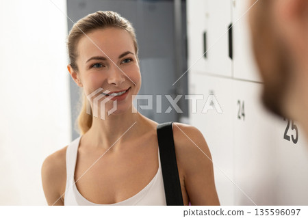 Man and woman talking in a gym after workout and looking excited Man and woman talking in a gym after workout and looking excited 135596097