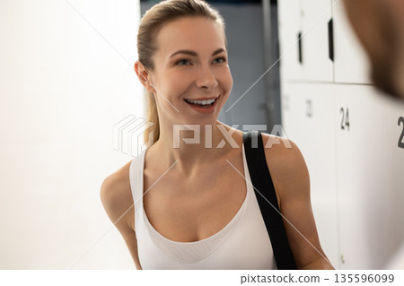 Man and woman talking in a gym after workout and looking excited Man and woman talking in a gym after workout and looking excited 135596099