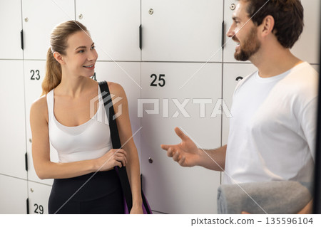 Man and woman talking in a gym after workout and looking excited 135596104