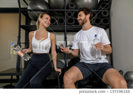 Young man and woman talking in the gym after a good workout Young man and woman talking in the gym after a good workout 135596188