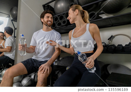 Young man and woman talking in the gym after a good workout Young man and woman talking in the gym after a good workout 135596189