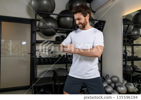 Dark-haired young sportsman exercising with elastic band and looking motivated 135596194