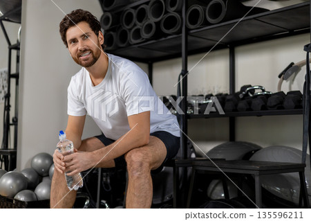 Handsome young bearded man in gym resting after workout 135596211