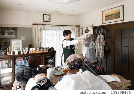 一位女士正在整理她父親的衣物。 135596456
