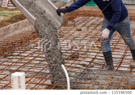 Closeup shot of concrete casting on reinforcing metal bars of floor in industrial construction site Closeup shot of concrete casting on reinforcing metal bars of floor in industrial construction site 135596500