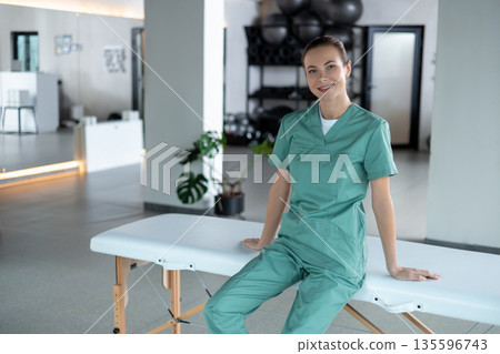 Woman physiotherapist sitting on couch smiling at camera preparing for session starting 135596743